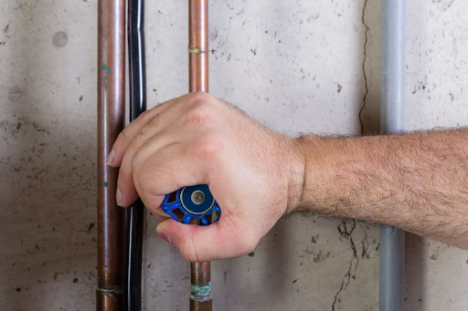 A man gripping a water shut-off valve.