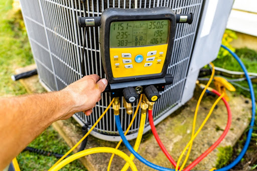 A technician checking the refrigerant in an outdoor AC unit.