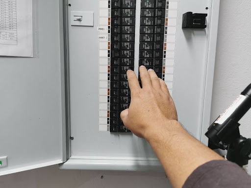 A man reaching for an electrical panel.